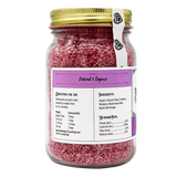 A glass jar with a gold lid holds Project Sudz | Berry Boost Urinary Support for Dogs and Cats – 210g, featuring pink shredded coconut flakes infused with cranberry. The mostly white and purple label highlights a natural, organic theme and includes ingredients, nutritional facts, serving sizes, and pet-use directions.