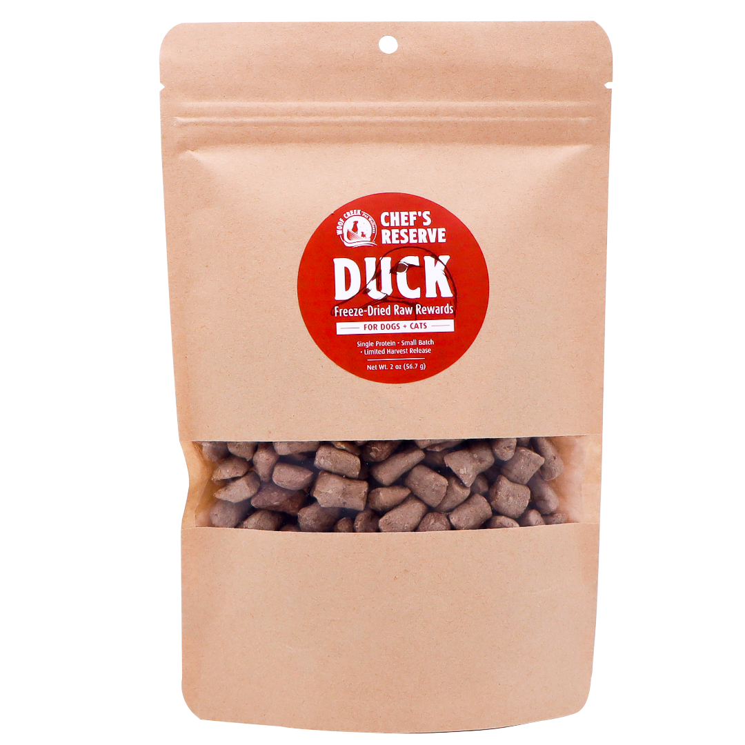 A brown resealable bag labeled Woof Creek Freeze-Dried Raw Duck Rewards | 2oz Pouch for Dogs + Cats, featuring visible brown treat pieces inside through a clear window. Perfect as high-value training rewards, these duck treats are irresistible for both dogs and cats.