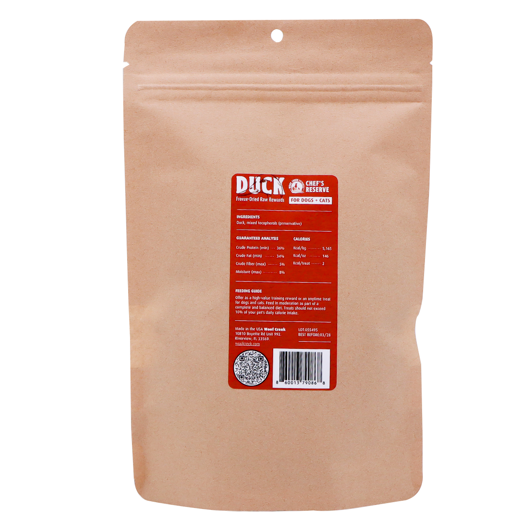 A brown resealable pouch labeled “Woof Creek Freeze-Dried Raw Duck Rewards | 2oz Pouch for Dogs + Cats” features a red and white label with nutritional information, a barcode, a QR code, and feeding instructions—making it easy for pet owners to offer their dogs or cats a high-value training reward or delicious treat.