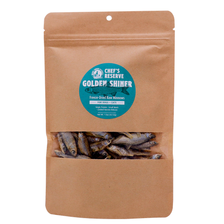 A brown resealable pouch with a clear window displays freeze-dried minnows inside. The label reads Woof Creek Golden Shiner Minnows | 1.5oz Pouch for Dogs + Cats. These nutritious morsels are perfect as dog treats or cat treats and make an excellent healthy reward for training.