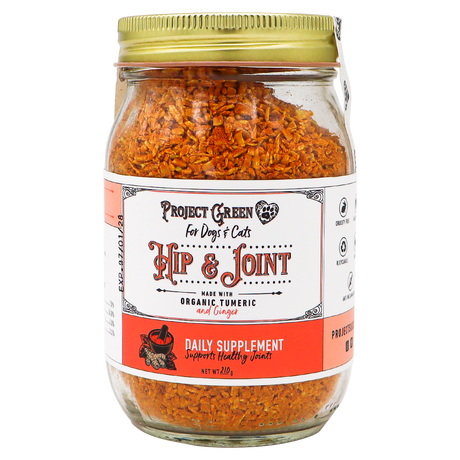 A glass jar with a gold lid containing orange flakes labeled Project Sudz | Hip & Joint Support for Dogs and Cats - 210g, featuring an advanced hip and joint formula with organic turmeric and ginger to support pet mobility.