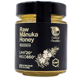 A glass jar of Center of Paradise | RAW MANUKA HONEY UMF 20+ MGO 850+ with a black label featuring the text UMF 20+ MGO 850+ and a botanical illustration of a flower branch.