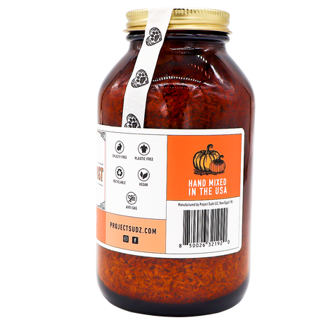 Project Sudz | Pumpkin Boost Digestive Health for Dogs and Cats - 210g comes in a large amber glass jar with a gold lid, containing dried orange contents designed to support your pet’s digestive health. The label displays icons for cruelty free, plastic free, moisture protection, and vegan. Next to a pumpkin illustration, text reads “Hand Mixed in the USA”—highlighting a blend of slippery elm and soil-based probiotics carefully crafted for your pet’s well-being.