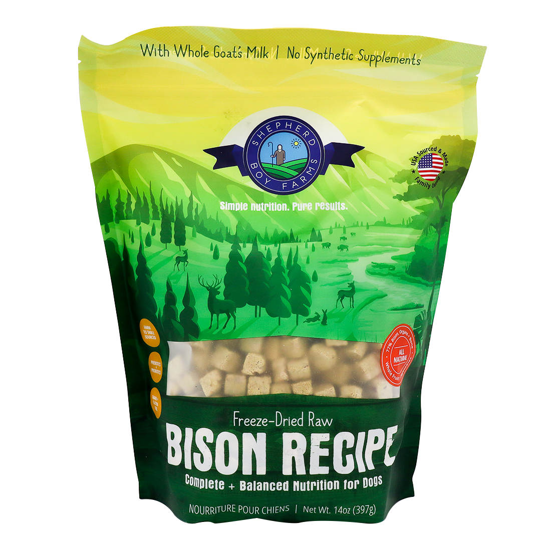 A green and yellow bag of Shepherd Boy Farms Freeze-Dried Bison Recipe (14oz) dog food, featuring a natural landscape with animals and trees. This grain-free recipe includes goat’s milk, no synthetic supplements, and is AAFCO approved.