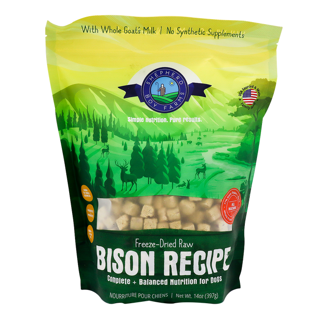 A green and yellow bag of Shepherd Boy Farms Freeze-Dried Bison Recipe (14oz) dog food, featuring a natural landscape with animals and trees. This grain-free recipe includes goat’s milk, no synthetic supplements, and is AAFCO approved.
