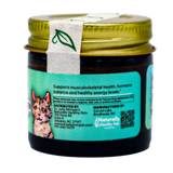 A small glass jar with a gold lid and a green leaf seal contains Dr. Judy's Elk Velvet Antler Powder for Cats (7g). The label displays a cat illustration, highlights the product’s health benefits including joint support, and includes contact information, a QR code, and distribution details.