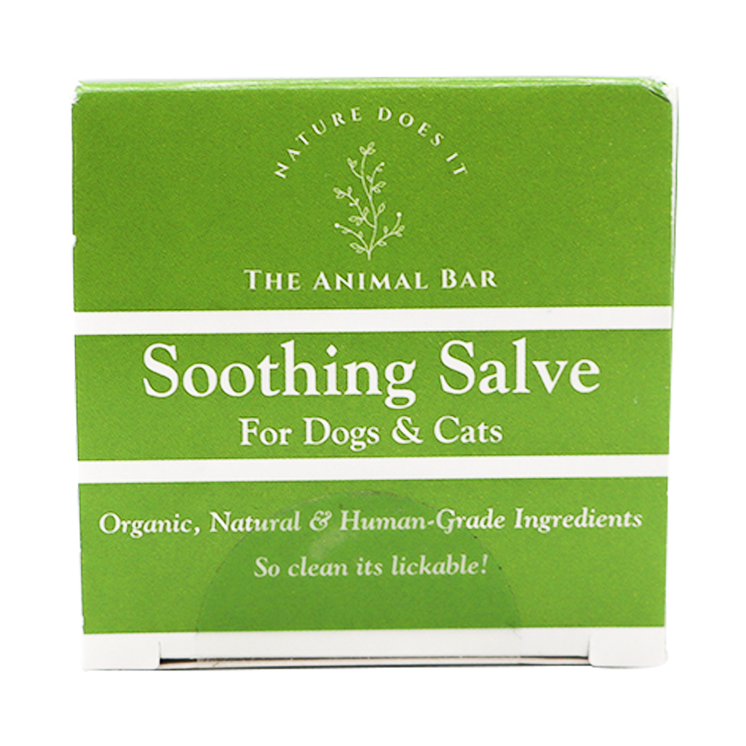 A green and white box labeled “The Animal Bar | Soothing Salve for Dogs & Cats - 2oz” features text emphasizing its organic, natural, human-grade ingredients with the slogan “So clean it’s lickable!” alongside a simple botanical graphic.
