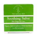 A green and white box labeled “The Animal Bar | Soothing Salve for Dogs & Cats - 2oz” features text emphasizing its organic, natural, human-grade ingredients with the slogan “So clean it’s lickable!” alongside a simple botanical graphic.
