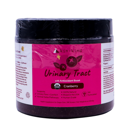 A jar of kin+kind Urinary Tract with Antioxidant Boost supplement for pets, featuring a cranberry flavor, comes in a pink and white label that displays its USDA organic certification and emphasizes its benefits for both dogs and cats. Vet-formulated, this top-tier organic pet supplement is designed to support optimal urinary tract health for your furry companions.