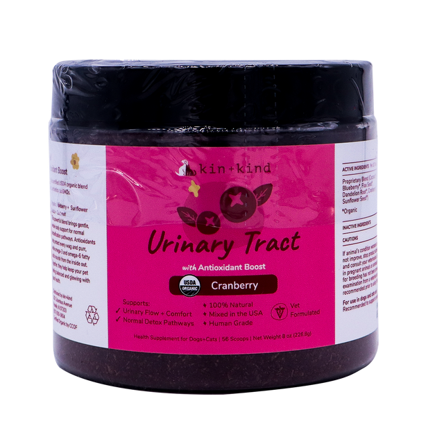 A jar of kin+kind Urinary Tract with Antioxidant Boost supplement for pets, featuring a cranberry flavor, comes in a pink and white label that displays its USDA organic certification and emphasizes its benefits for both dogs and cats. Vet-formulated, this top-tier organic pet supplement is designed to support optimal urinary tract health for your furry companions.