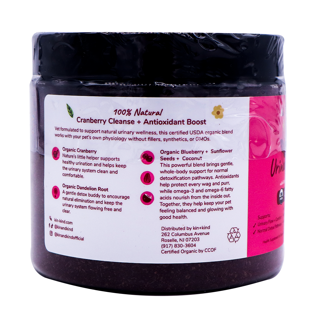 A dark jar labeled “kin+kind Urinary Tract with Antioxidant Boost” features a pink and white design, showcasing details about its USDA organic ingredients, urinary tract health benefits, and company contact information. The label also emphasizes its blend of powerful superfoods formulated as pet supplements.