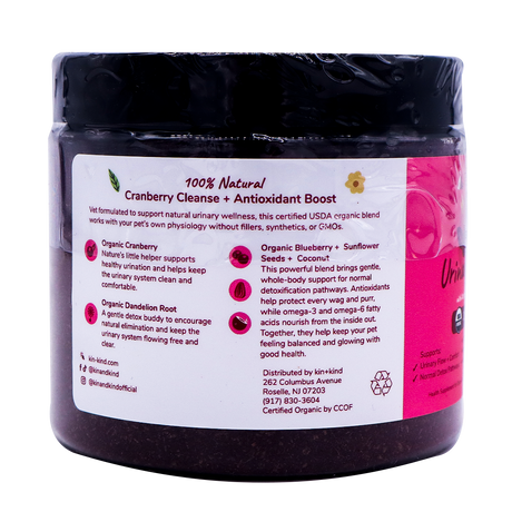 A dark jar labeled “kin+kind Urinary Tract with Antioxidant Boost” features a pink and white design, showcasing details about its USDA organic ingredients, urinary tract health benefits, and company contact information. The label also emphasizes its blend of powerful superfoods formulated as pet supplements.